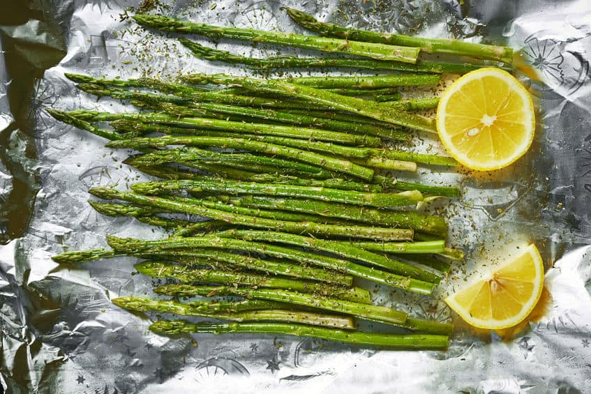 A pile of fresh asparagus on foil ready for the oven