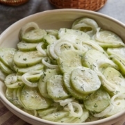 A bowl of food on a plate, with Cream and Cucumber