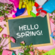 spring cleaning creative bright concept. tools, bottles, flowers, chalkboard with words hello spring