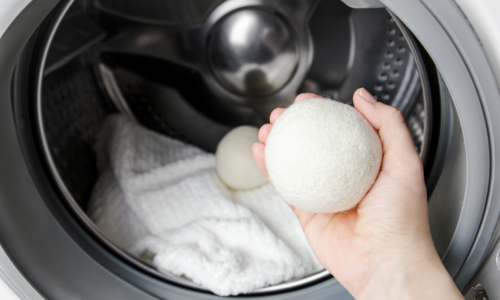 wool dryer balls hand placing into laundry dryer
