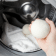 wool dryer balls hand placing into laundry dryer