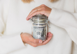 emergency fund Young Caucasian Woman Holding Hands Glass Bank with Cash Money Dollars Bills