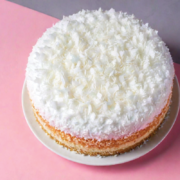 overhead angle of a coconut cake covered in white frosting and lots of shredded coconut on a midcentury countertop