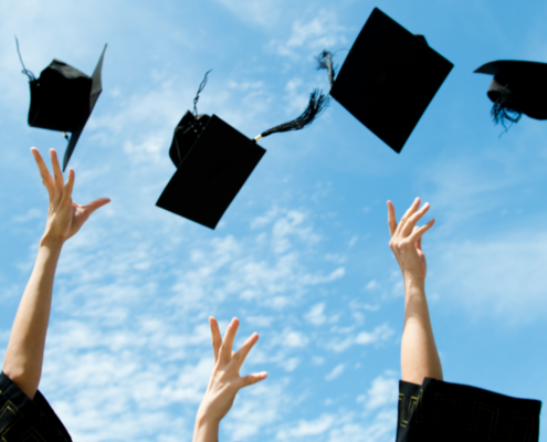 graduation gifts three throwing caps up into blue sky.