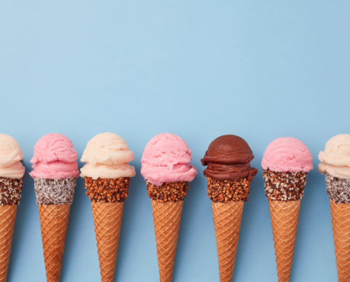 ice cream waffle cones lined up with vanilla strawberry and chocolate scoops