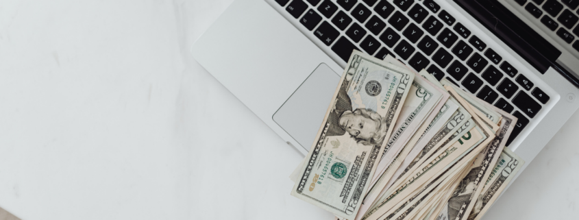 Twenty dollar bills sitting on macbook laptop