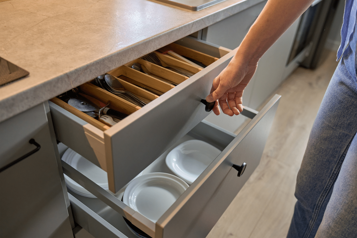 kitchen drawer being opened to show utensils and plates