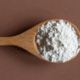 a large wooden spoon holding cornstarch ready to use around the house
