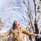 young woman arms out with first snowfall during the Christmas holidays
