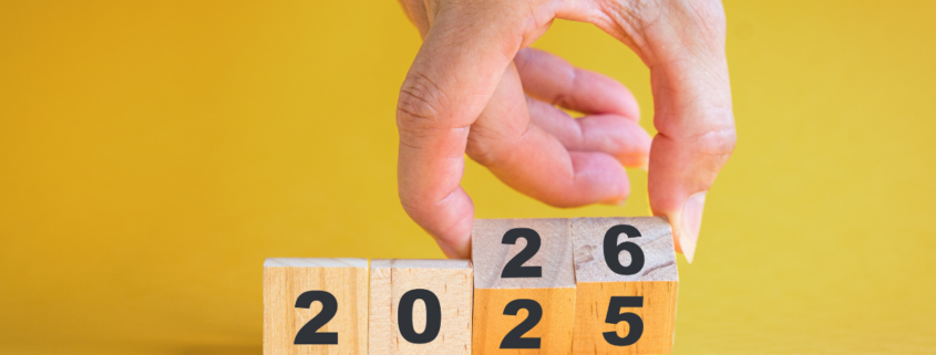 26 ways to save $5 a day. male hand flipping over wooden blocks with year from 2025 to 2026