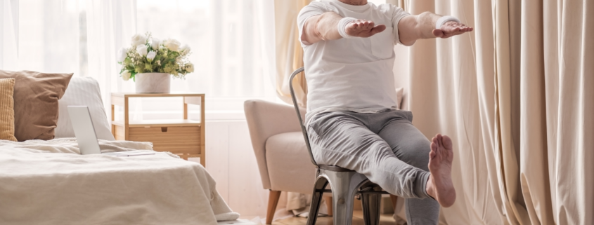 free chair yoga for seniors older man extending leg and arms in bright natural lit bedroom