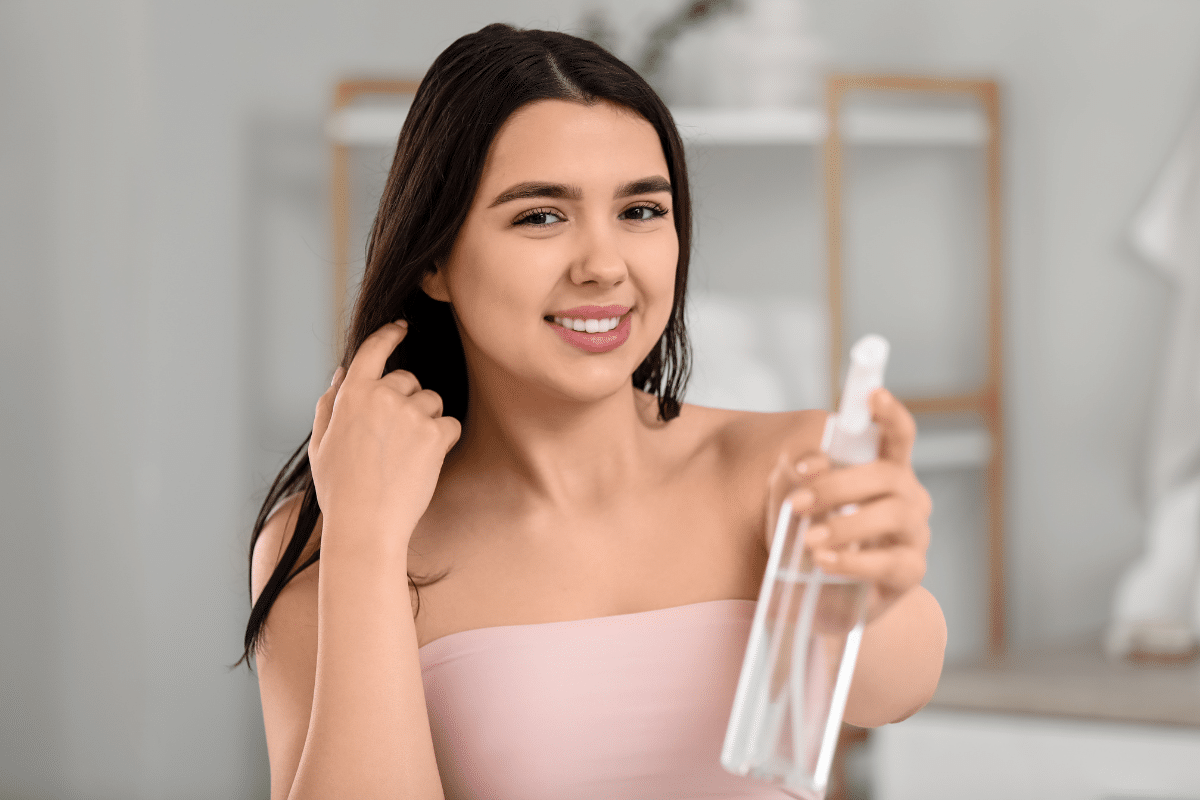 Young Woman with Natural Spray to Get Rid of Flyaways in Bathroom