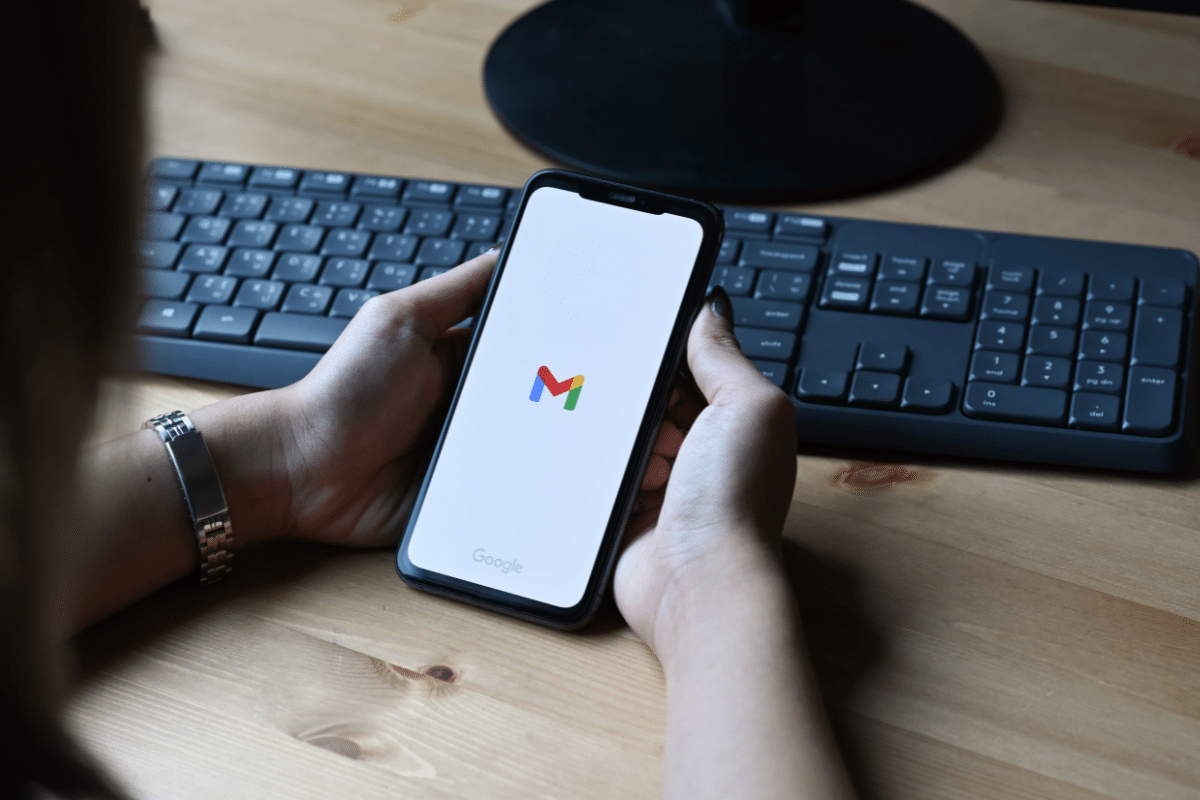 man holding iphone opening gmail app to safelist an email address