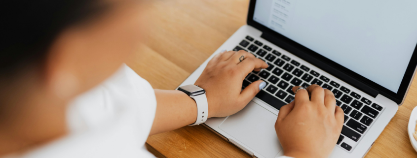 woman typing on laptop keyboard learning how to safelist an email address.