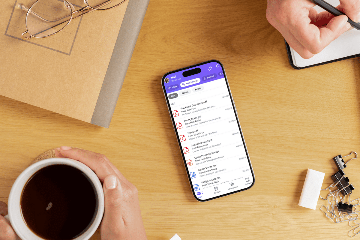 yahoo mail app open on iphone sitting on workspace with binder clips mug of coffee