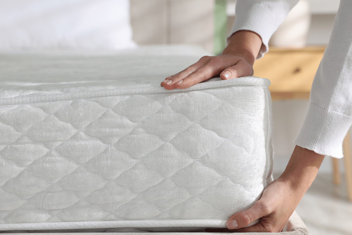 woman placing new mattress on bedframe february deals