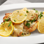 creamy lemon garlic chicken recipe in white plate lemon slices fresh basil