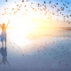 woman spreading arms at signt of birds flocking on beach sunrise financial freedom gap how to spend less earn more and be free budge