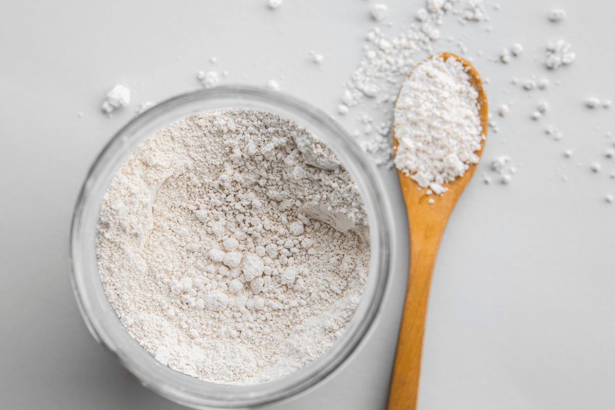 Diatomaceous Earth in glass bowl and wooden spoon