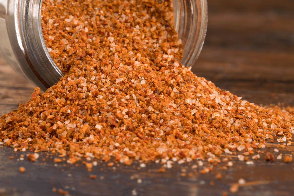 emerils original essence copycat spice blend spilling out of glass jar
