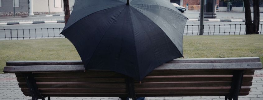 best inexpensive umbrella person sitting on park bench