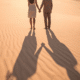 young couple holding hands standing on the beach no spend year