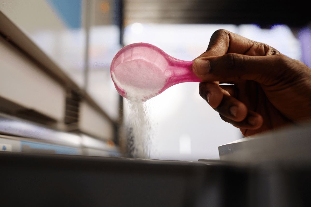 male hand pouring citric acid into dishwasher compartment diy cleaner