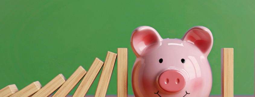 simple money habits keystone habit piggy bank and a row of dominoes