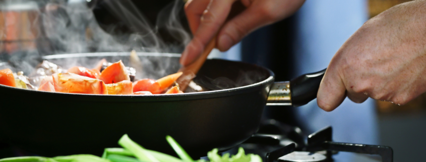 common kitchen mistakes woman stirring vegetales in a pan on the cooktop