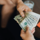 male lending money to family member twenty and fifty dollar bills
