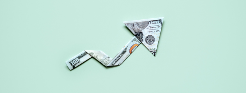 up arrow folded origami hundred dollar bill on green background fight inflation at home
