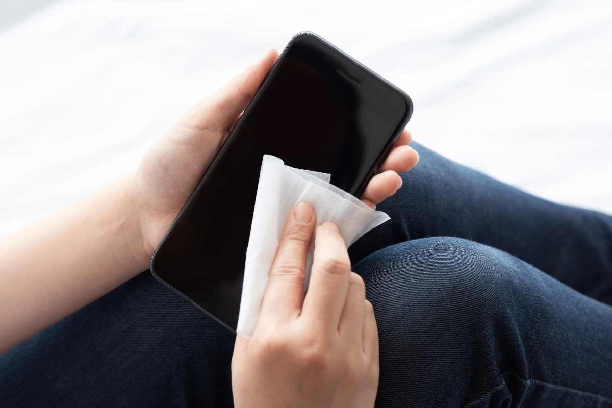 woman wiping iphone with 70% isopropyl alcohol disinfecting wipe