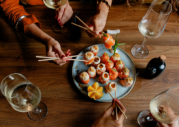 how to stop overspending on dining out friends enjoying fancy sushi dinner with wine
