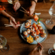 how to stop overspending on dining out friends enjoying fancy sushi dinner with wine