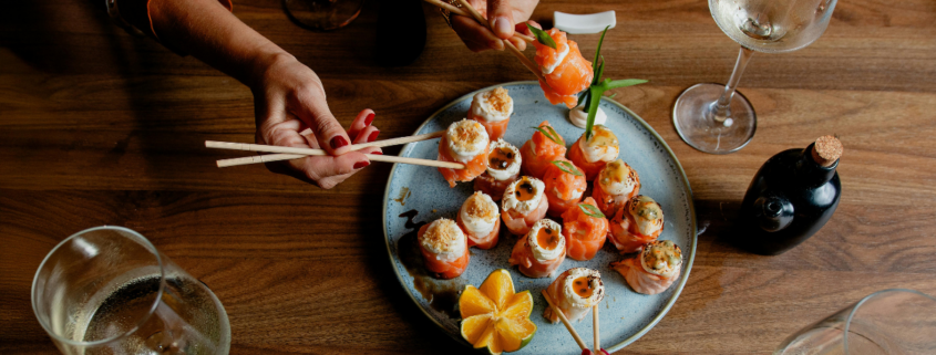 how to stop overspending on dining out friends enjoying fancy sushi dinner with wine