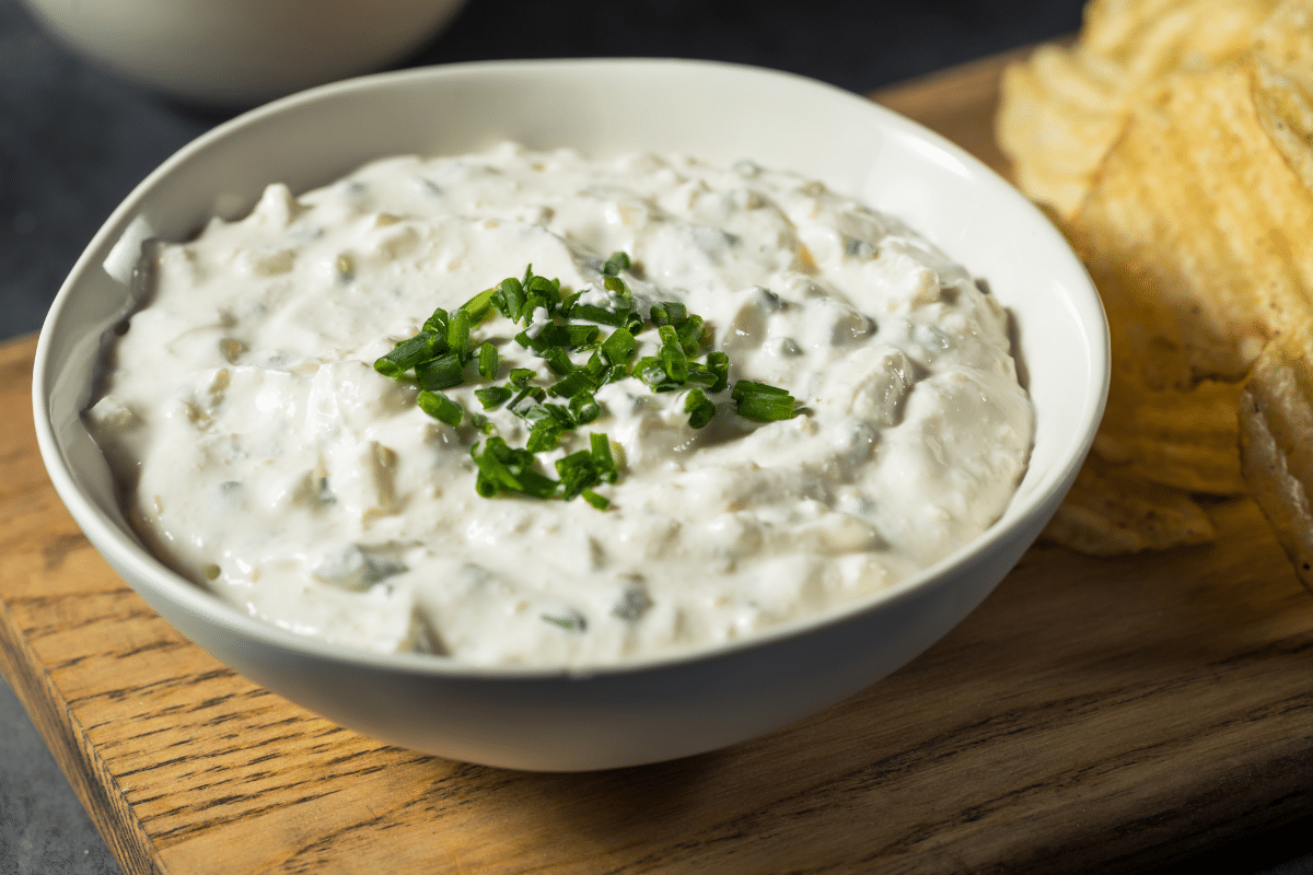 close up of fresh french onion dip homemade with ruffle potato chips in background