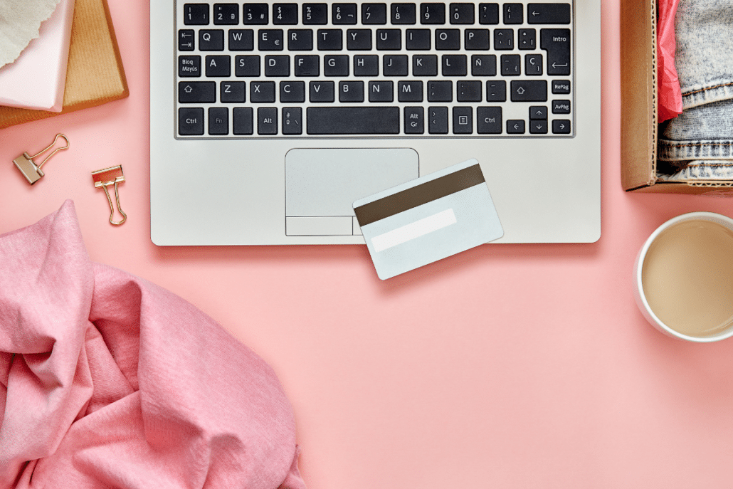 materialism leads to discontentment overhead shot of laptop credit card on pink desk
