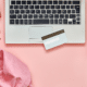 materialism leads to discontentment overhead shot of laptop credit card on pink desk