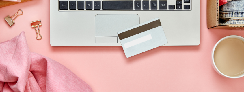 materialism leads to discontentment overhead shot of laptop credit card on pink desk