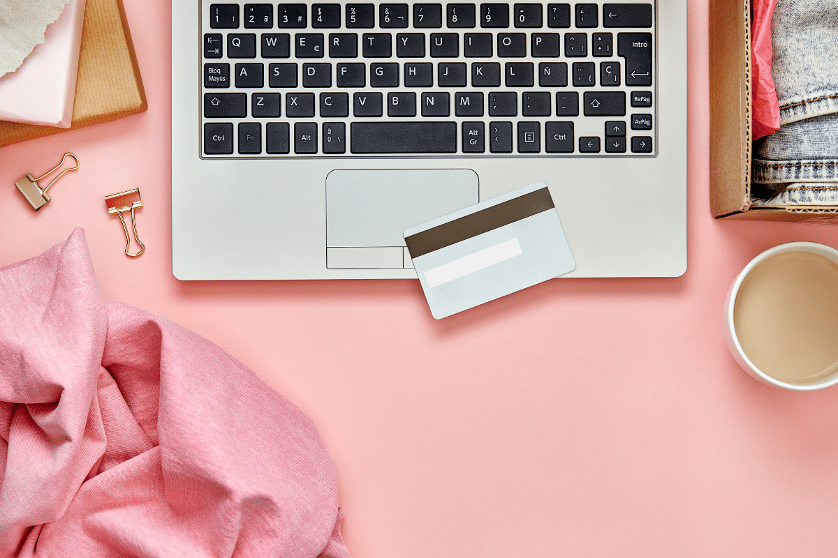 materialism leads to discontentment overhead shot of laptop credit card on pink desk