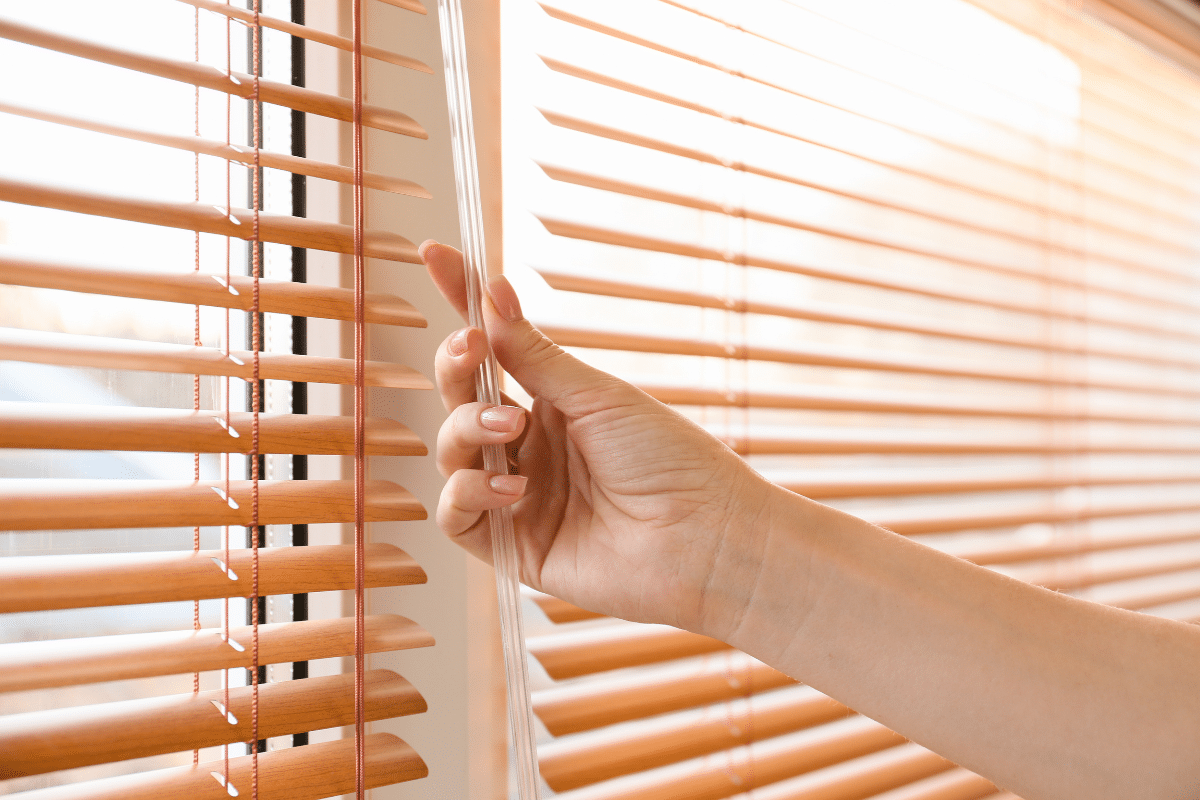woman opening blinds with bright light pouring in
