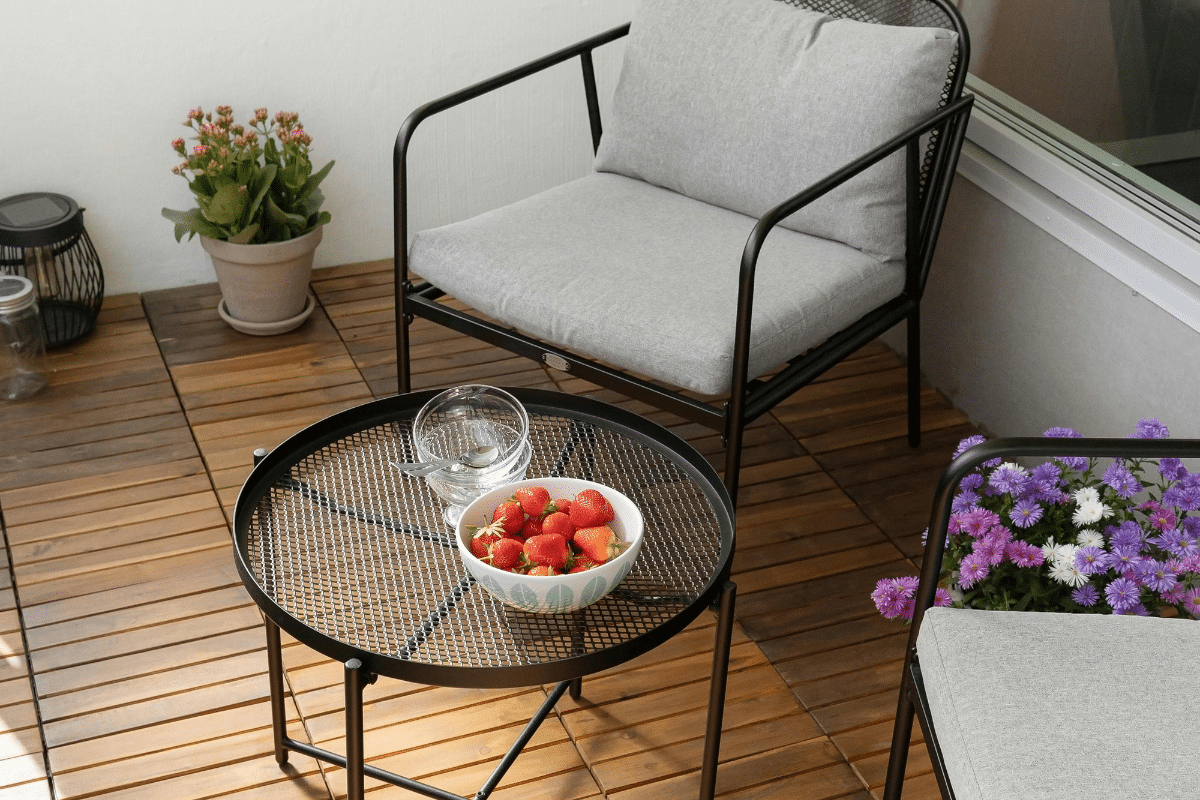 simple backyard sitting area two chairs table with bowl of strawberries and fresh potted flowers and shade