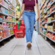 woman walking with basket down store aisle grocery items with the biggest price increases