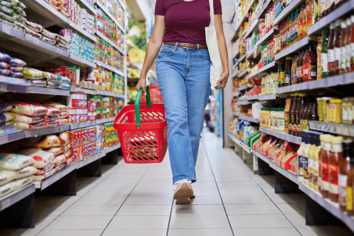 woman walking with basket down store aisle grocery items with the biggest price increases