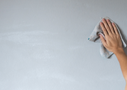 female hand wiping painted wall with microfiber cloth