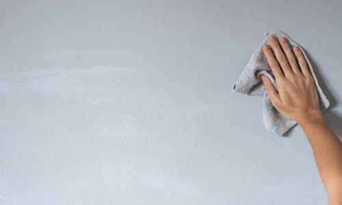 female hand wiping painted wall with microfiber cloth