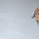 female hand wiping painted wall with microfiber cloth