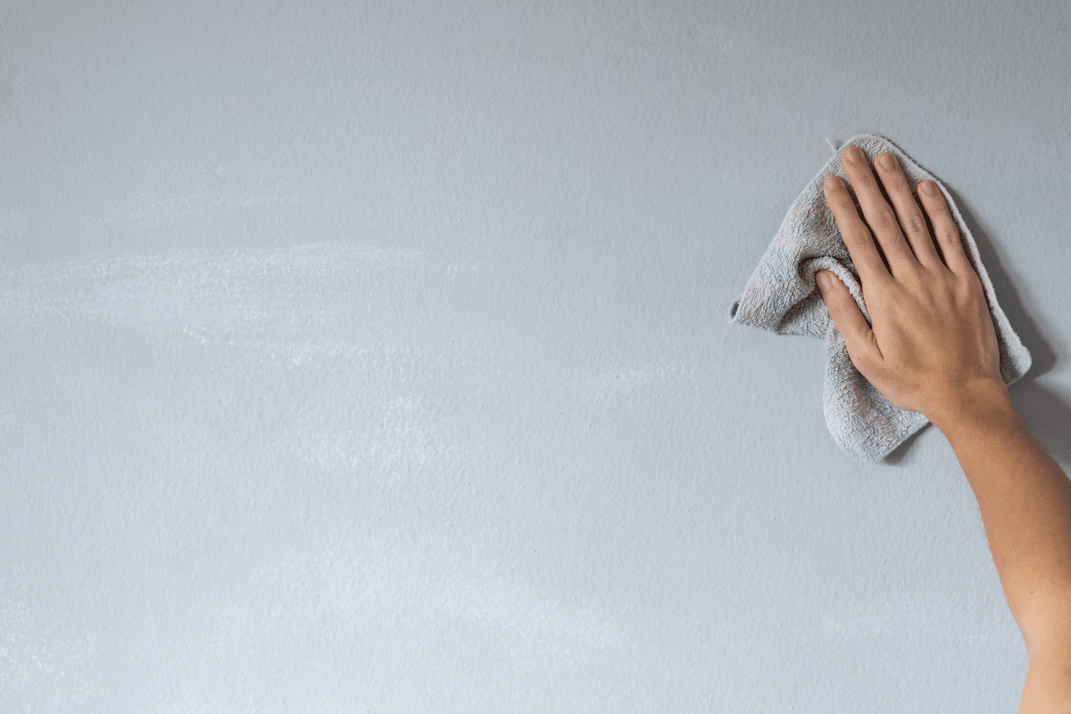 female hand wiping painted wall with microfiber cloth