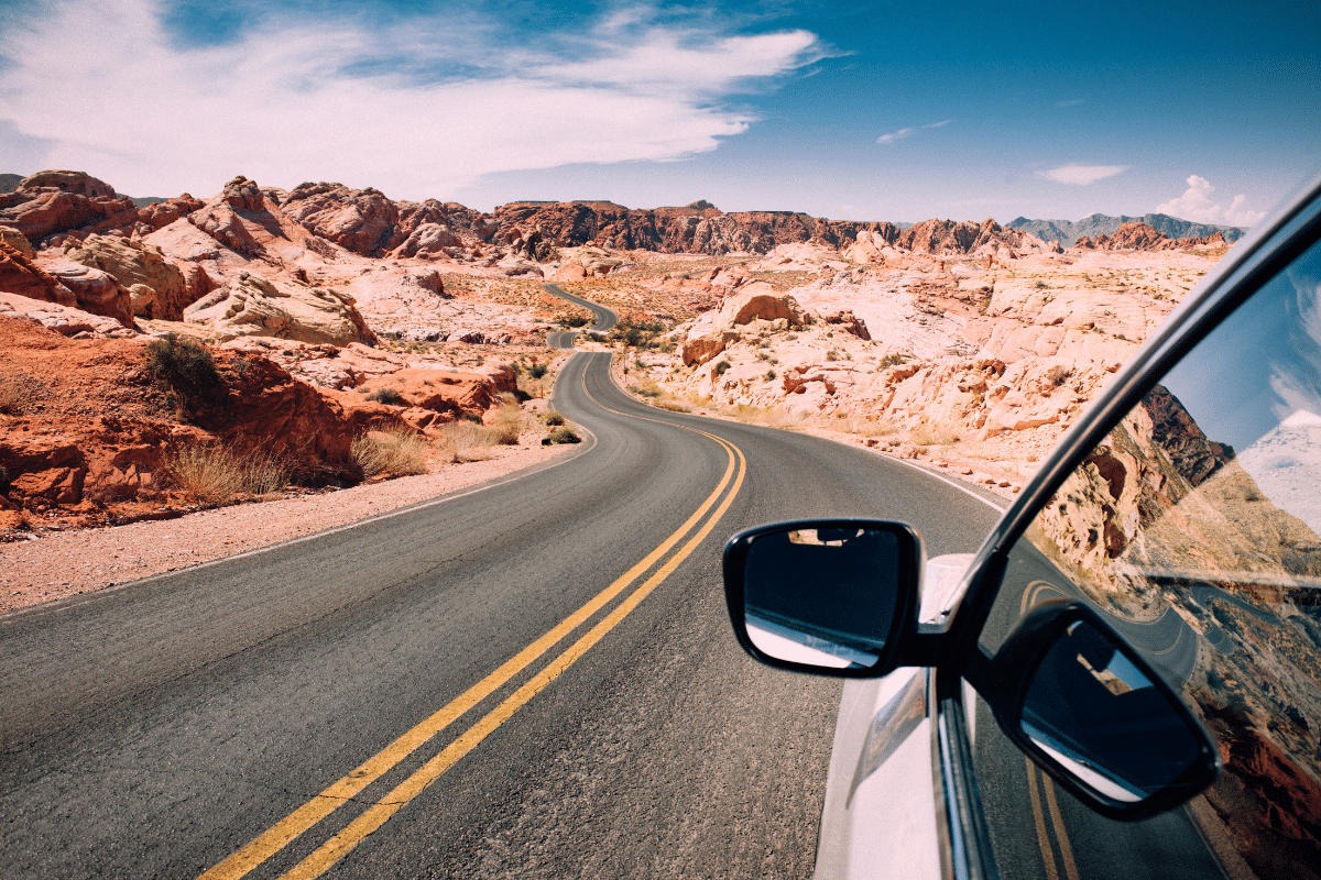 road trip car checklist car driving through the desert winding road with blue skies