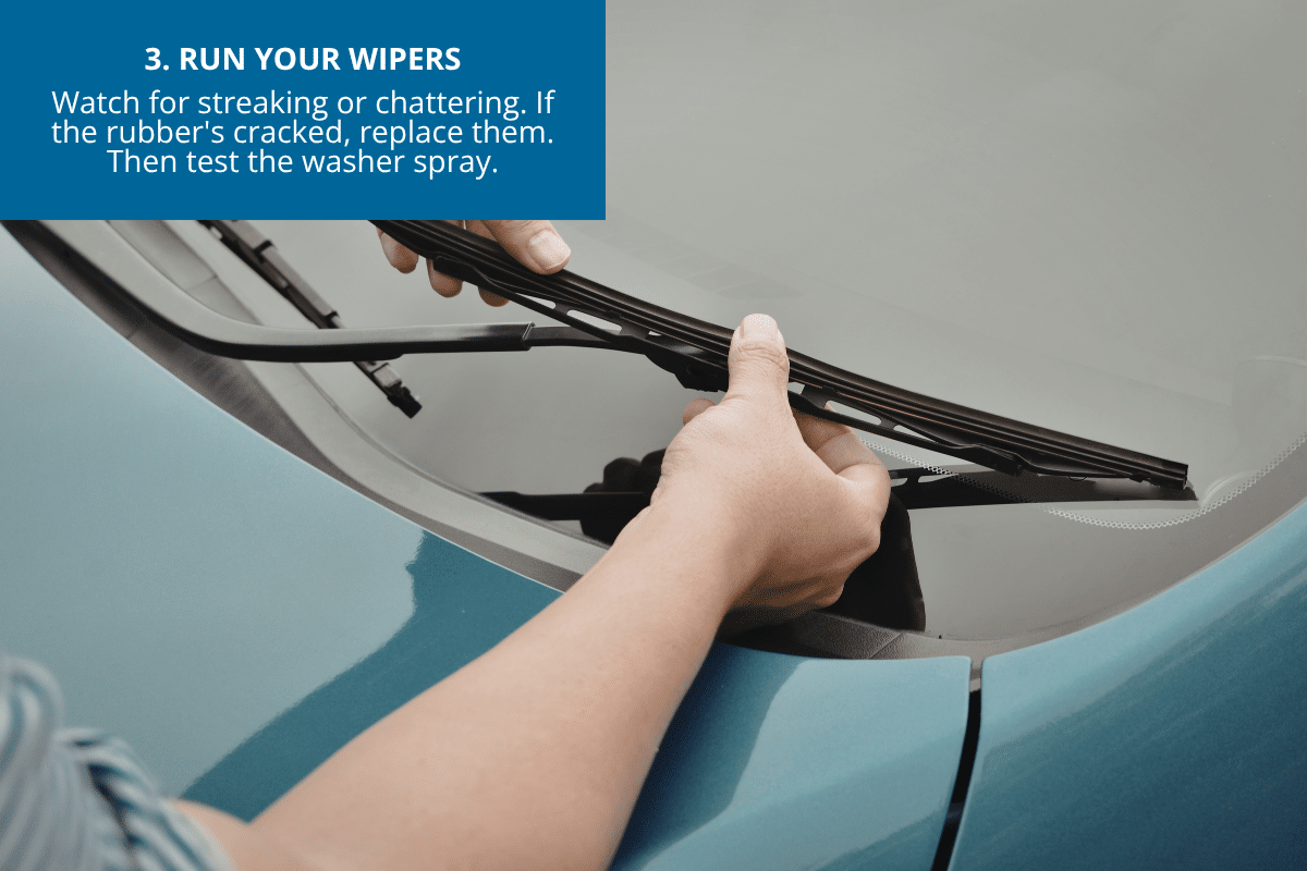 road trip checklist for your car woman checking windshield wipers for cracks